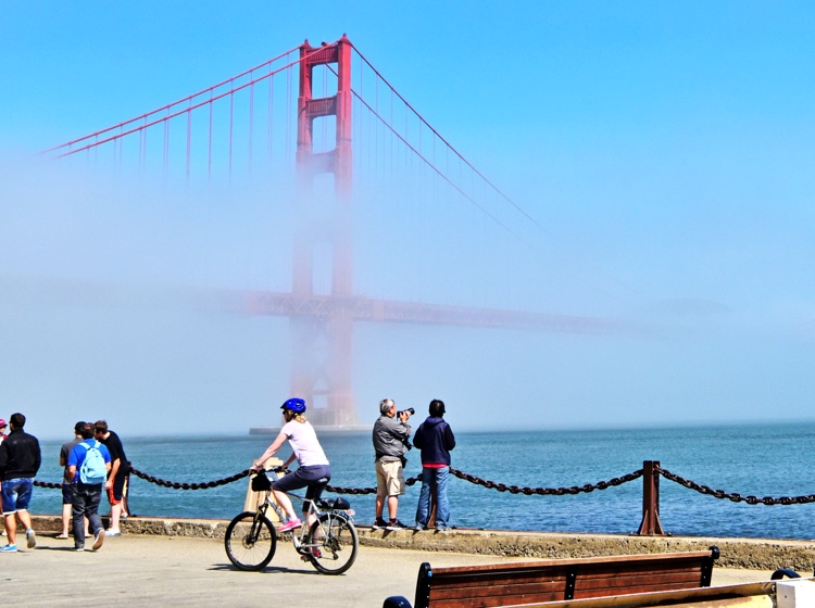 People biking and walking in front of the Golden Gate Bridge